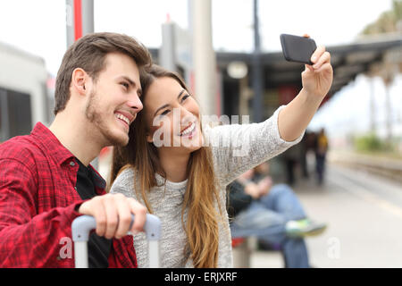 Couple de voyageurs photographier une avec un smartphone selfies dans une gare Banque D'Images