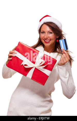 Jolie femme avec un beau sourire portant un rouge Santa hat holding a big red Christmas gift box et de cartes bancaires qu'elle célèbre sa séance de magasinage réussie Banque D'Images