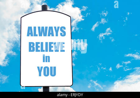 Toujours croire en vous motivational quote written on white road sign isolated over clair fond de ciel bleu. Concept image avec copie espace disponible Banque D'Images