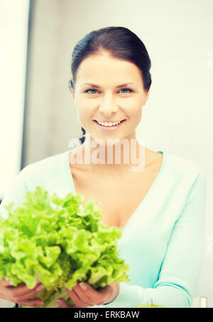 Femme dans la cuisine avec des feuilles de salade verte Banque D'Images