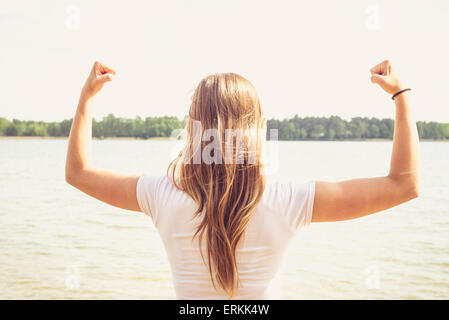 Fille est pointant ses mains vers le ciel à la manière de succès, elle est debout dans l'eau. Banque D'Images