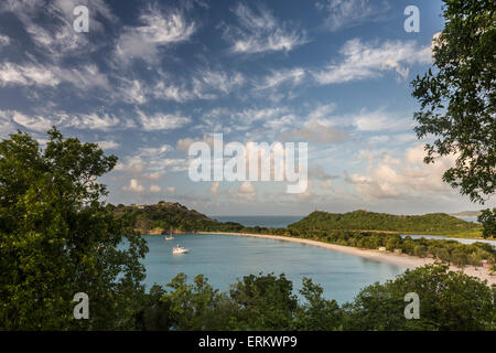 Les nuages sont éclairés par le soleil couchant sur la baie profonde une bande de sable caché par une végétation luxuriante, Antigua, Iles sous le vent Banque D'Images