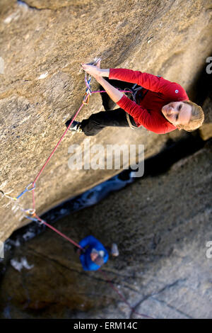 L'ascension d'une femme petite fissure au-dessus de son partenaire d'assurage et une rivière de Yosemite National Park, en Californie. Banque D'Images