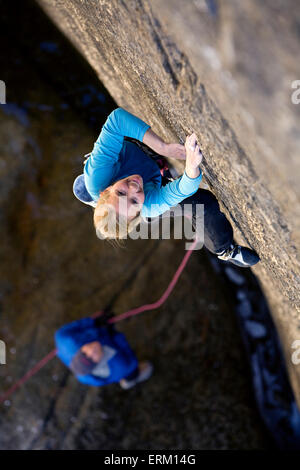 L'ascension d'une femme petite fissure au-dessus de son partenaire d'assurage et une rivière de Yosemite National Park, en Californie. Banque D'Images