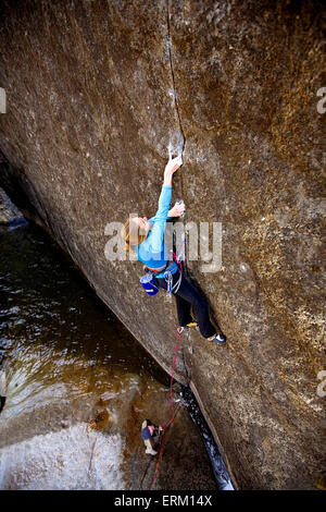 L'ascension d'une femme petite fissure au-dessus de son partenaire d'assurage et une rivière de Yosemite National Park, Californie (high angle view). Banque D'Images