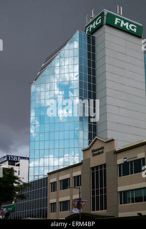 Bâtiment FMG reflétant ciel bleu et nuages duveteux contre un fond de ciel gris un jour de pluie à Palmerston North, Nouvelle-Zélande Banque D'Images