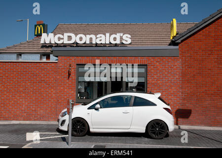 Le conducteur d'une voiture en attente d'être servis à la trappe du lecteur dans d'un restaurant McDonalds Banque D'Images