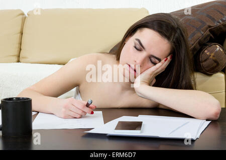 Étudiante fatigué et dormir dans sa chambre à coucher sur les notes alors qu'étudiait. Jeune femme dans le salon de l'apprentissage, elle est Banque D'Images