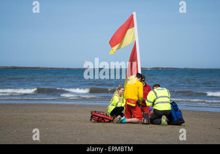 Responers Rnli et paramédicaux, d'abord traiter la victime sur la plage Banque D'Images