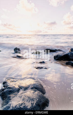 Surf éclaboussures sur les rochers après le lever du soleil ; Wailua, Kauai, Hawaii, United States of America Banque D'Images