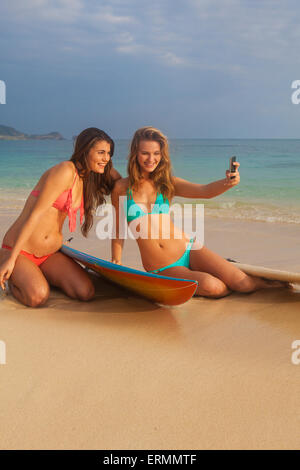 Les soeurs à la plage avec téléphone cellulaire ; Kailua, île de Hawaii, Hawaii, United States of America Banque D'Images