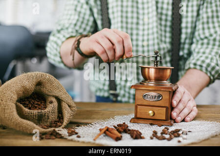 Les grains de café barista falsification dans un moulin à café en bois Banque D'Images