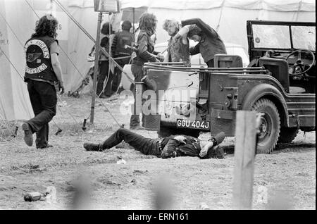 Scène à Pop Festival, Weeley, Essex, à la suite d'une bataille entre les hommes de la sécurité et de Hells Angels, un Hells Angel allongé sur le sol, d'autres vus par un véhicule, le 28 août 1971. Banque D'Images