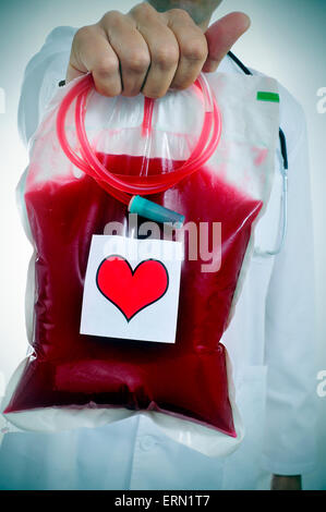 Libre d'un médecin tenant une poche de sang avec un autocollant d'un cœur rouge Banque D'Images