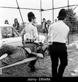 Scène à Pop Festival, Weeley, Essex, à la suite d'une bataille entre les hommes de la sécurité et de Hells Angels, un jeune blessé Hells Angel est emmené sur une civière par la police, le 28 août 1971. Banque D'Images