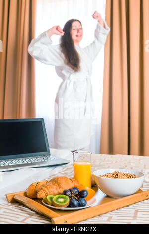 Petit-déjeuner au lit et s'étend lui-même une femme en peignoir Banque D'Images