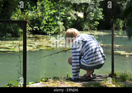 Un garçon dans une chemise rayée poissons dans le soleil Banque D'Images