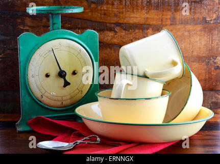 Balance de cuisine vintage et de l'étain tasses et les casseroles sur fond sombre bois usagé. Banque D'Images