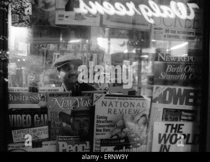 Chicago, IL, 14-Dec-1996 : un journal de fin de soirée à l'intérieur de l'homme au cours de son petit kiosque dans le centre-ville de Chicago. Banque D'Images