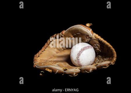 Baseball usé s'insère dans un vieux gant de baseball sur un solide fond noir. Image a été allumé à l'aide d'une technique de lightpainting Banque D'Images