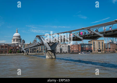 Les gens de marcher à travers Millenium Bridge sur la Tamise, avec Saint Pauls cathédrale en arrière-plan, London, UK Banque D'Images