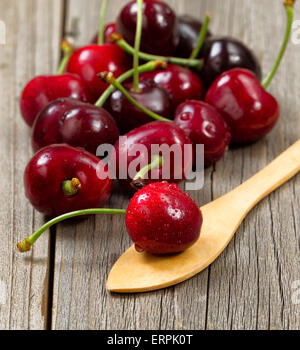 Close up image cerises entières fraîchement cueillies, focus on cherry en cuillère, sur bois rustique. Banque D'Images