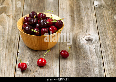 Close up image de cerises noires entières fraîchement cueillis dans un bol sur la table en bois rustique. La mise en page en format horizontal. Banque D'Images