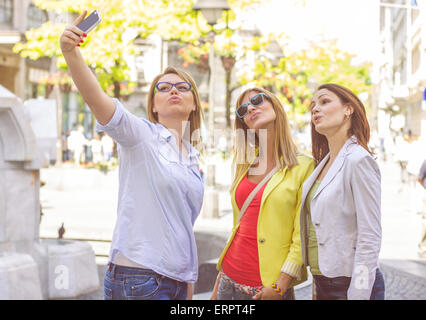 Happy Female Friends avec Selfies téléphone sur la rue.vie amitié.Caucasian girl taking photo urbain avec le mobile. Banque D'Images