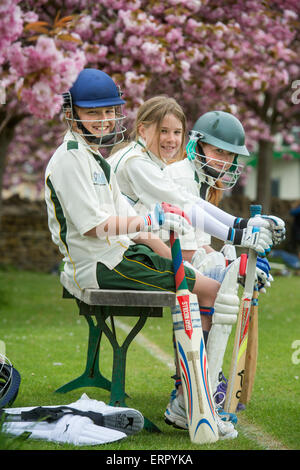 Trois jeunes filles en attente de bat à un match de cricket junior filles dans le Wiltshire UK Banque D'Images