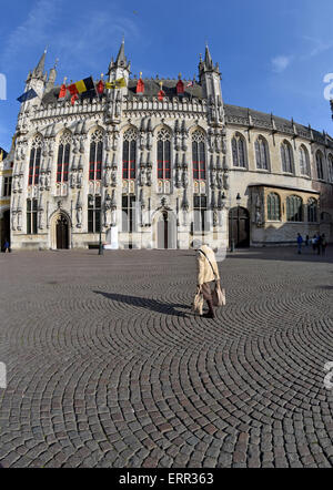 Une femme plus âgée avec les sacs en passant devant la mairie de place Burg, Bruges, Belgique Banque D'Images