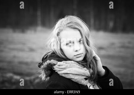 Portrait en extérieur gros plan de beau blond Caucasian teenage girl dans une forêt au printemps, noir et blanc photo stylisée Banque D'Images
