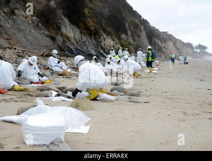 Continuer une équipe de nettoyage pour nettoyer le sable et les roches huileuses pendant les efforts visant à réduire les dommages causés par un pipeline pause à Rufugio State Beach le 6 juin 2015 à Santa Barbara, en Californie. Plus de 105 000 litres de pétrole brut s'est déversé à partir d'un pipeline dans l'une des plus belles sections du littoral de l'état. Banque D'Images