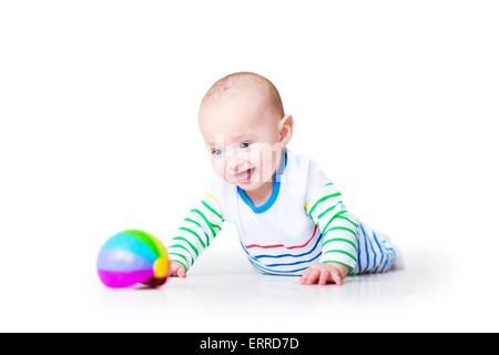 Heureux rire funny baby boy portant une chemise colorée apprendre à ramper en jouant sur son ventre, sur fond blanc Banque D'Images