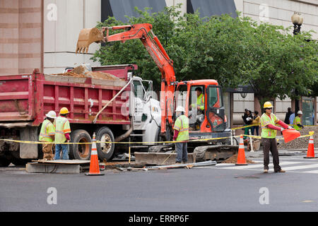 Les travailleurs de la construction à l'aide municipale - pelleteuse USA Banque D'Images