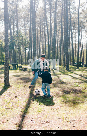 Père et fils joue au soccer dans forest Banque D'Images