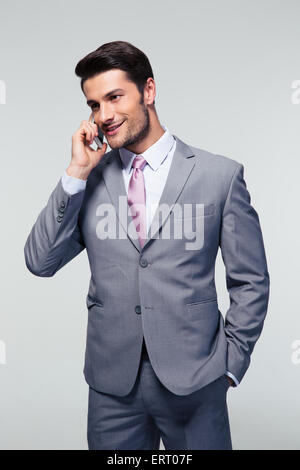 Happy businessman talking on le téléphone sur fond gris. À l'écart Banque D'Images