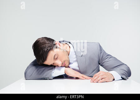 Businessman sleeping sur la table sur fond gris Banque D'Images