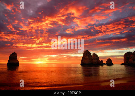 Superbe lever de soleil sur l'océan avec de beaux nuages rouges et quelques falaises hors de l'eau permanent Banque D'Images