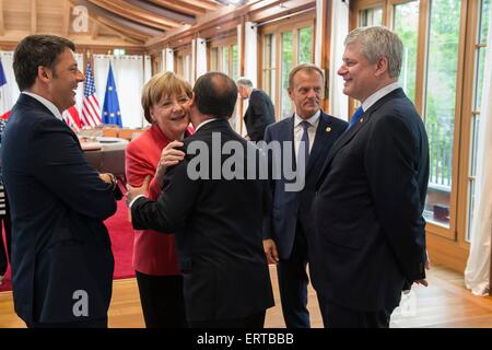 La chancelière allemande Angela Merkel reçoit le président français François Hollande en tant que Premier Ministre Italien Matteo Renzi (à gauche), premier ministre canadien Stephan Harper, et le président du Conseil européen, Donald Tusk, regardez sur le deuxième jour de la réunion au sommet du G7 au Schloss Elmau resort 8 juin 2015 en Allemagne, Krun. Banque D'Images