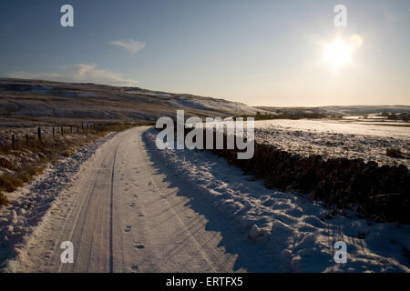 Empreintes de pas sur une route couverte de neige au coucher du soleil, Glen Whilly, nouveau Luce, Dumfries et Galloway, Écosse Banque D'Images