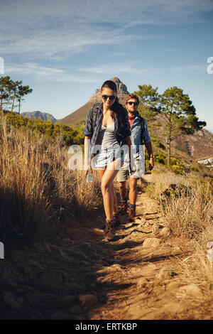 Jeune couple trekking vacances d'été ensemble, dans la campagne au cours d'une journée ensoleillée. Caucasian hiker couple walking par pathwa Banque D'Images