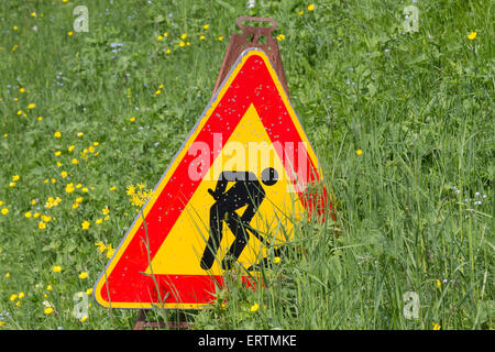 L'homme au travail signer partiellement couvert par un champ d'herbe verte Banque D'Images