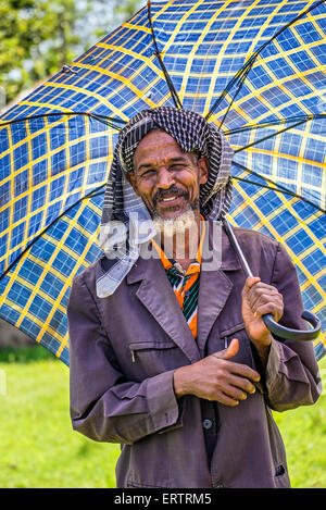 Vieux homme éthiopien avec un parapluie sur une journée chaude. Banque D'Images