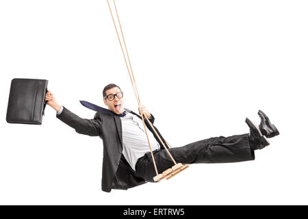 Portrait d'un jeune homme d'affaires heureux swinging sur une balançoire et tenant une valise isolé sur fond blanc Banque D'Images