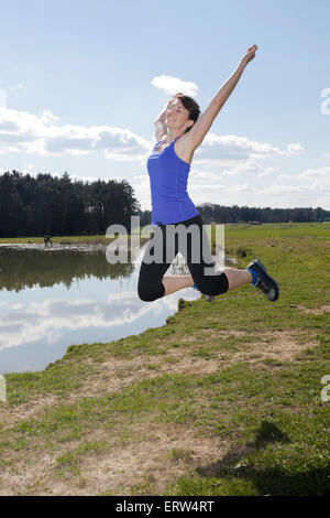 Jeune femme en tenue de sport jumping outdoors Banque D'Images