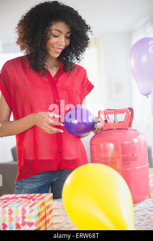 Mixed Race woman de gonfler les ballons à l'hélium pour partie Banque D'Images