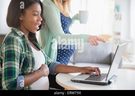 Les femmes enceintes à l'aide d'ordinateur portable à table Banque D'Images