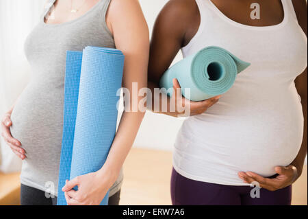 Les femmes enceintes exerçant son tapis de yoga Banque D'Images
