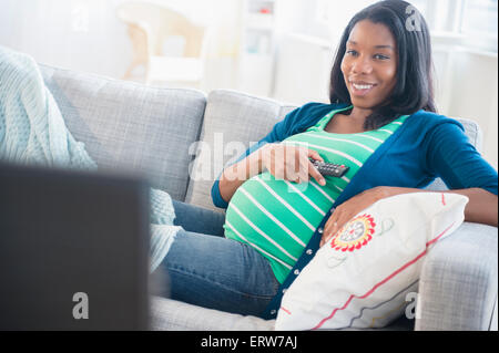 Femme enceinte noir regarder la télévision sur le canapé Banque D'Images