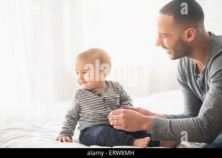 Père jouant avec son bébé sur le lit Banque D'Images